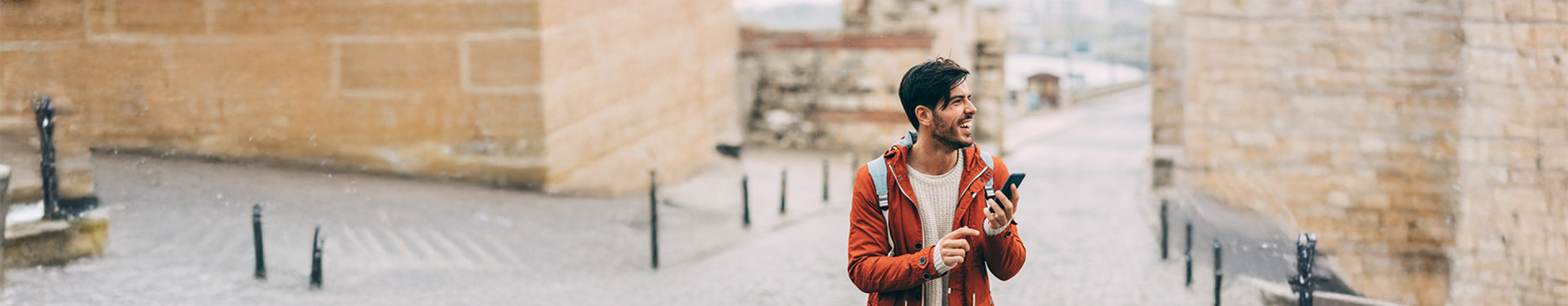 Smiling man holding phone in city