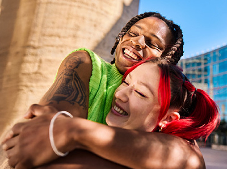 Couple hugging outside a building and a stone wall