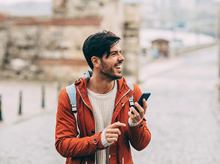 Smiling man with phone and backpack