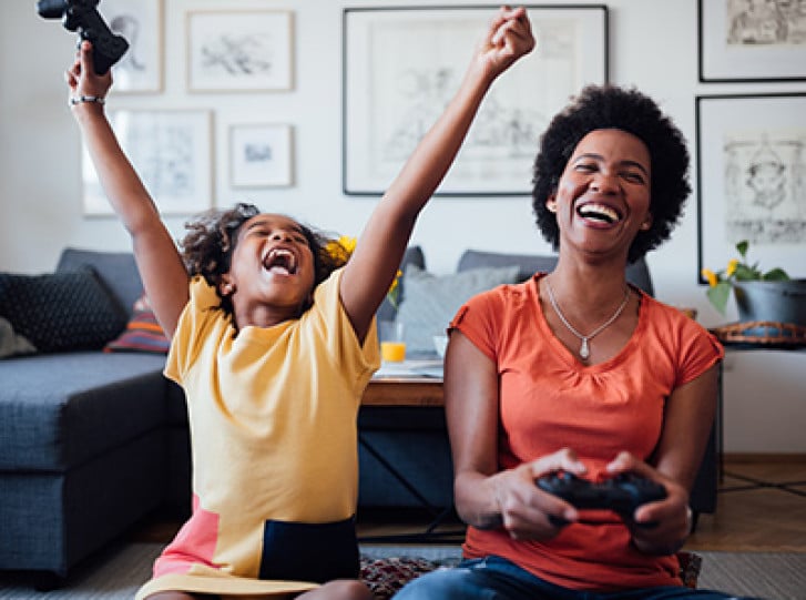 Mother and daughter on sofa playing video games