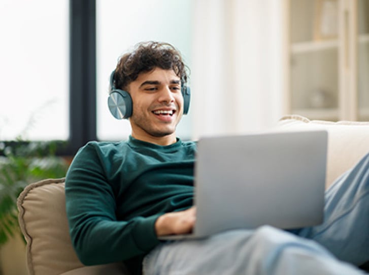 Smiling man with headphones on using laptop
